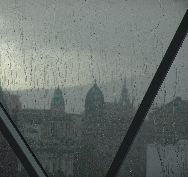 Fensterscheibe mit Regentropfen, Häuser im Hintergrund