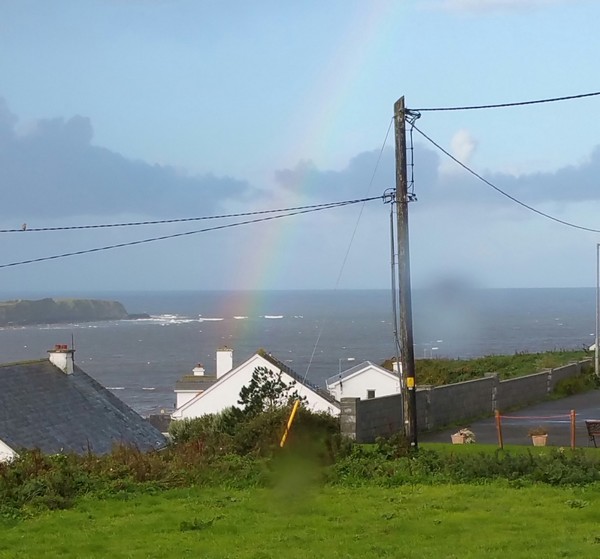 Bild von einem Regenbogen und Häusern vor einer Küste